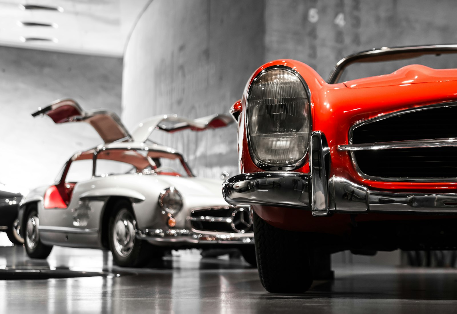 Zwei Oldtimer vor einer Betonwand